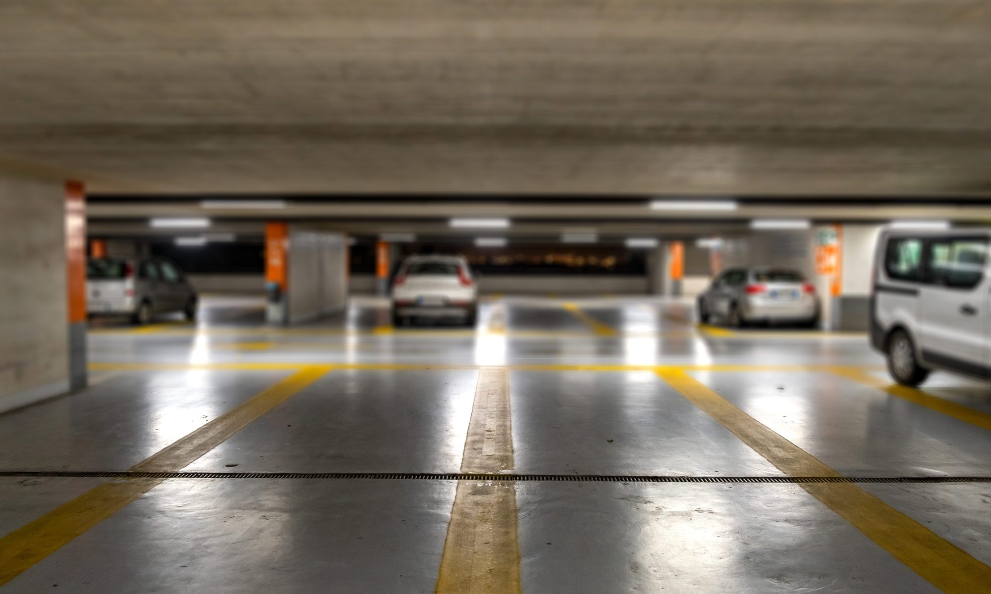 Yellow markings with blurred modern cars parked inside closed underground parking lot.